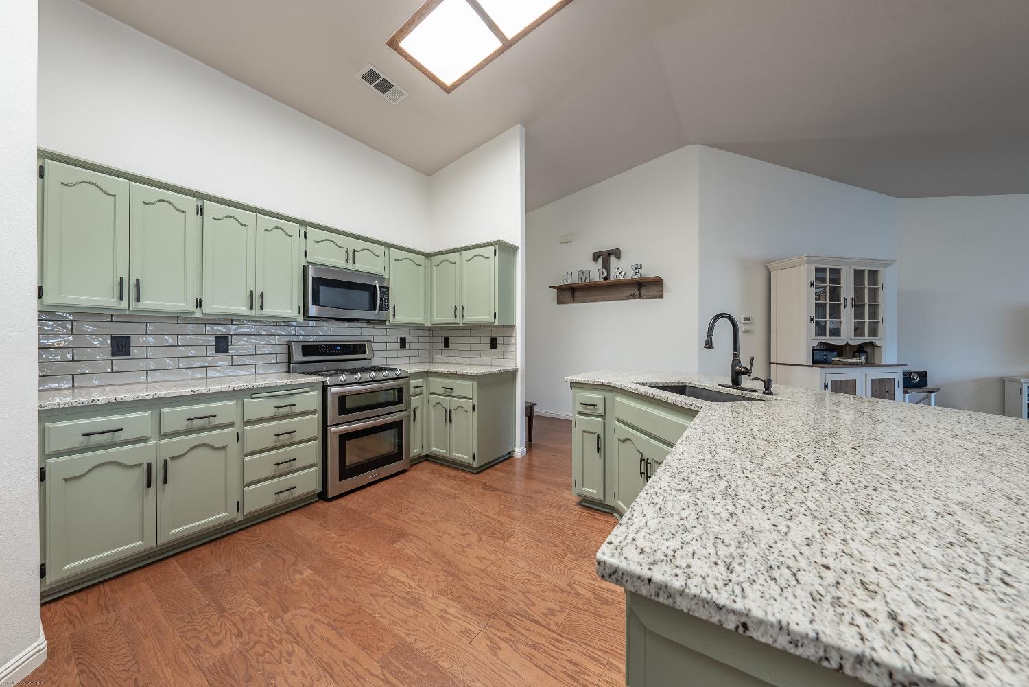 695 Crescent Lane Lemoore, CA 93245 - Photo 14 of 47 a kitchen with stainless steel appliances granite countertop a stove top oven a sink dishwasher and white cabinets with wooden floor