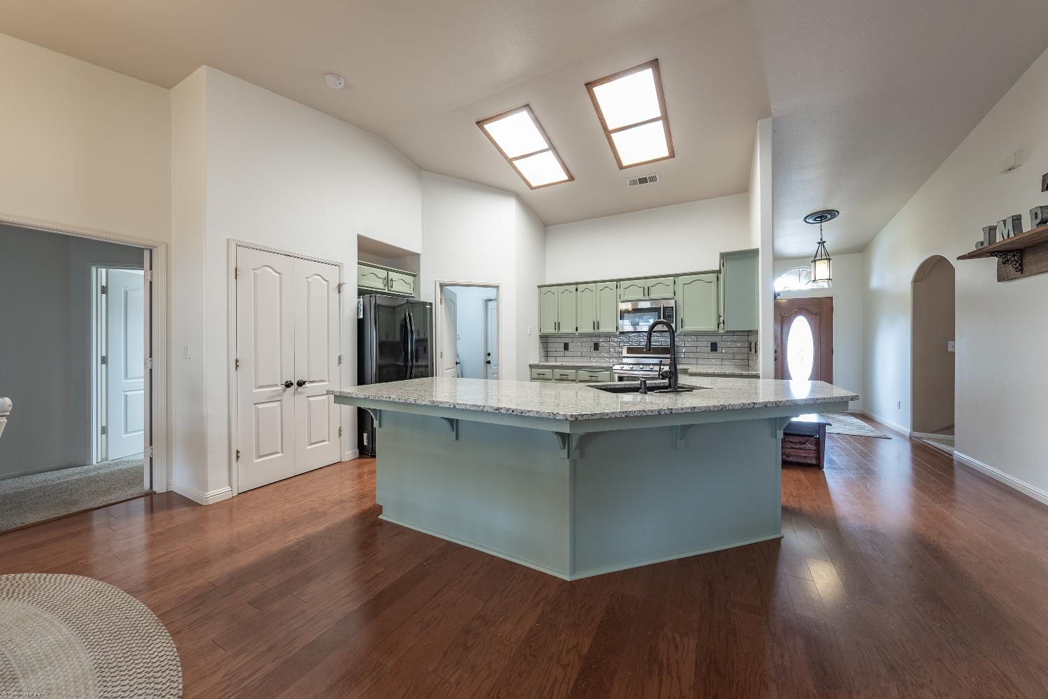 695 Crescent Lane Lemoore, CA 93245 - Photo 9 of 47 a kitchen with stainless steel appliances granite countertop a refrigerator a sink dishwasher a stove and a dining table with wooden floor