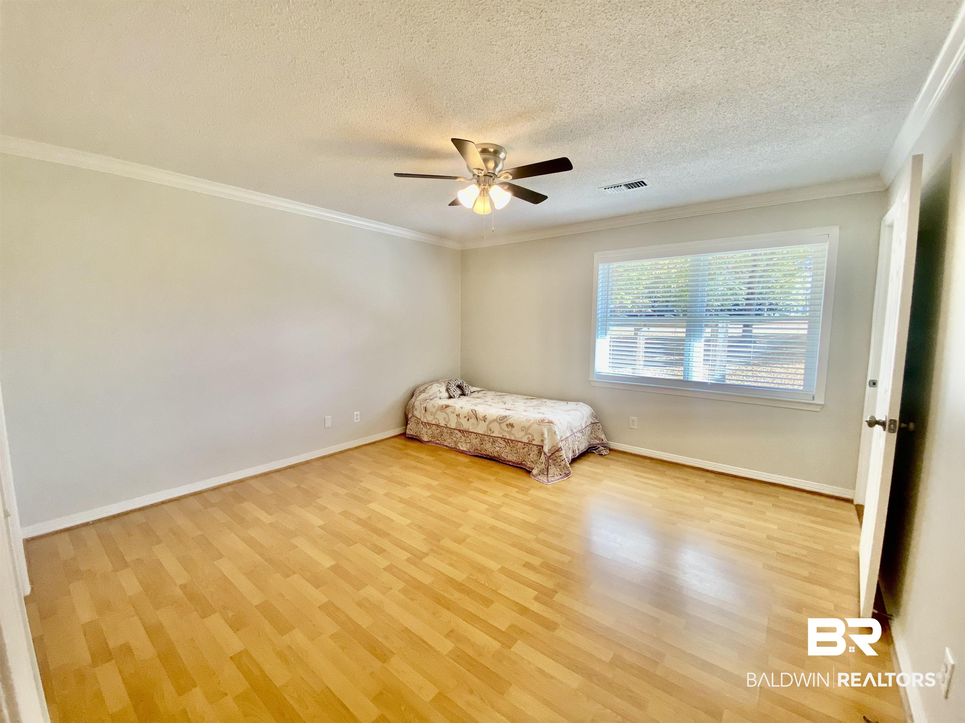 265 Azalea Drive Monroeville, AL 36460 - Photo 22 of 39 Unfurnished bedroom with ceiling fan, a textured ceiling, light wood-type flooring, and ornamental molding