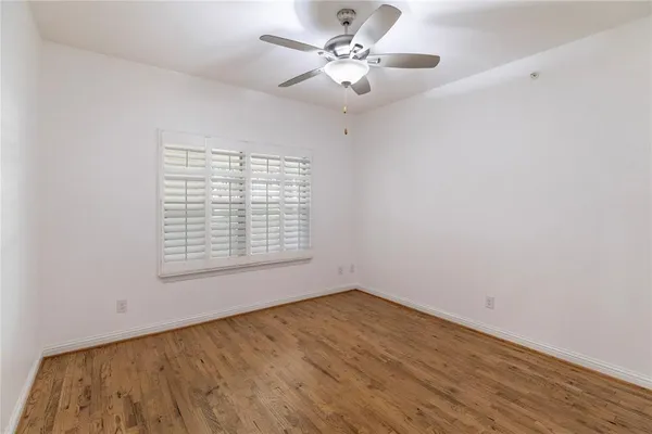 an empty room with wooden floor and a ceiling fan