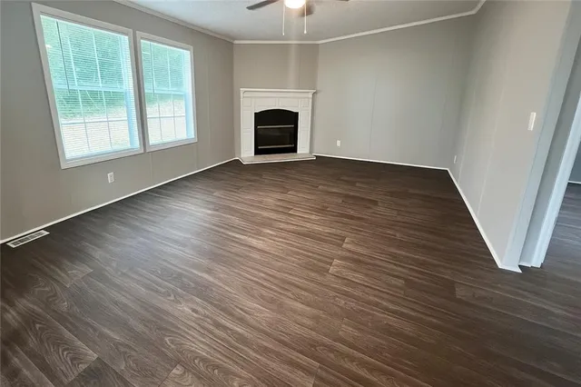 an empty room with wooden floor fireplace and windows