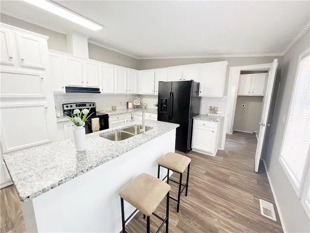 a kitchen with granite countertop a refrigerator and a stove top oven