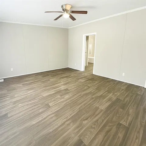 an empty room with wooden floor ceiling fan and windows