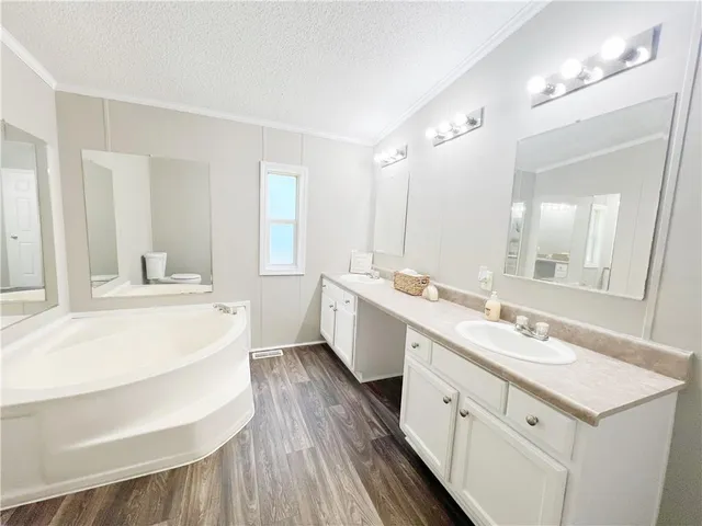 a large white bathroom with a double vanity sink a mirror and a bathtub