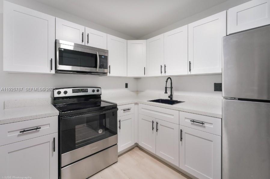 12215 West Dixie Highway, Unit 306 North Miami, FL 33161 - Photo 4 of 7 a kitchen with white cabinets and stainless steel appliances