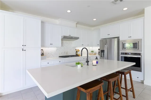 a kitchen with stainless steel appliances granite countertop a table chairs sink and cabinets