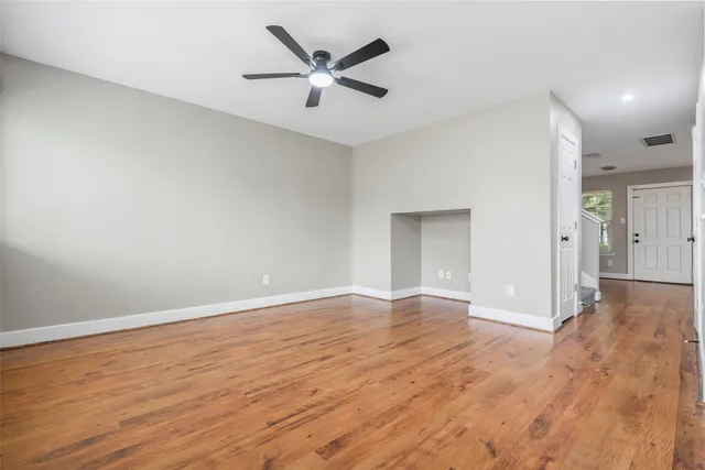 an empty room with wooden floor and a ceiling fan