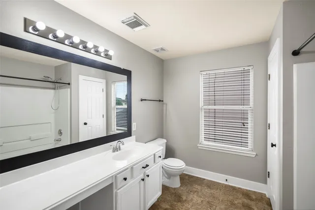 a bathroom with a sink a toilet and a large mirror