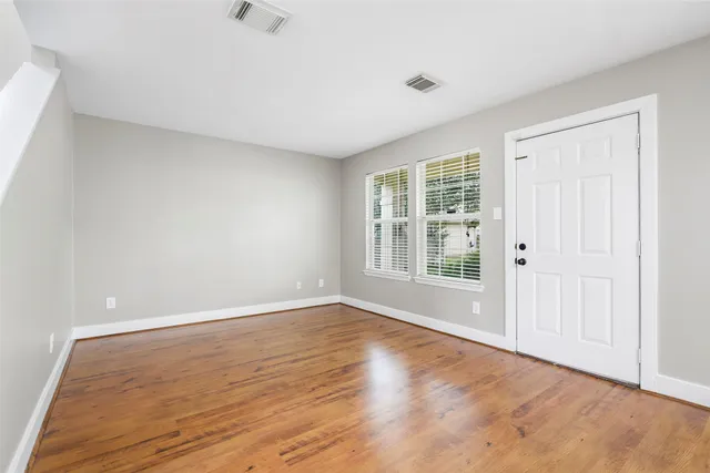 a view of an empty room with wooden floor and a window