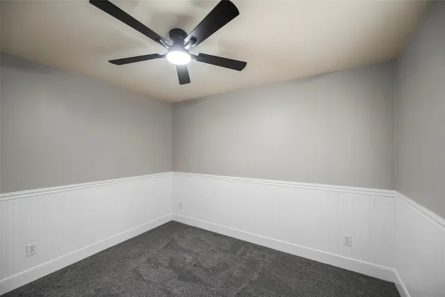 an empty room with a chandelier fan and windows