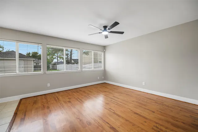 a view of empty room with wooden floor and fan