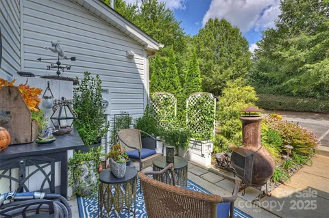 a view of a patio with table and chairs potted plants and a house