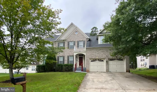 a front view of a house with garden and trees