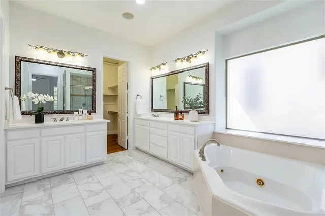 a large white bathroom with a bathtub sink and mirror