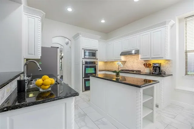 a kitchen with stainless steel appliances granite countertop a sink stove and refrigerator
