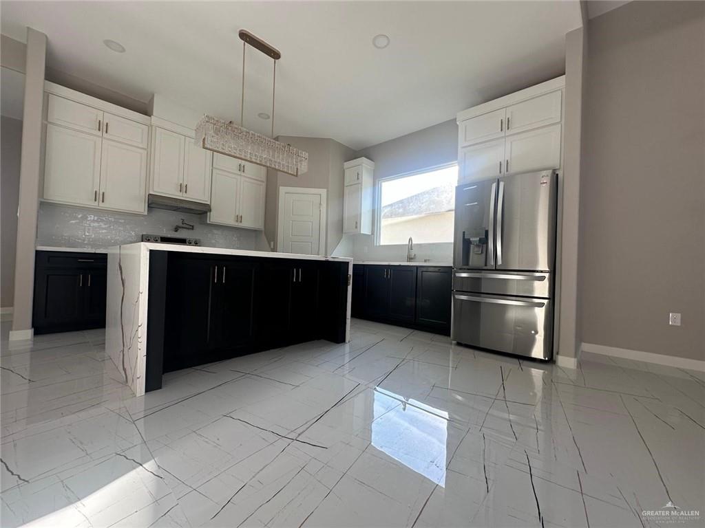 909 Azalea Street Mission, TX 78573 - Photo 3 of 29 other view of the Kitchen featuring stainless steel fridge with ice dispenser, two tone cabinetry, light marble finish floors, a kitchen island, and decorative backsplash
