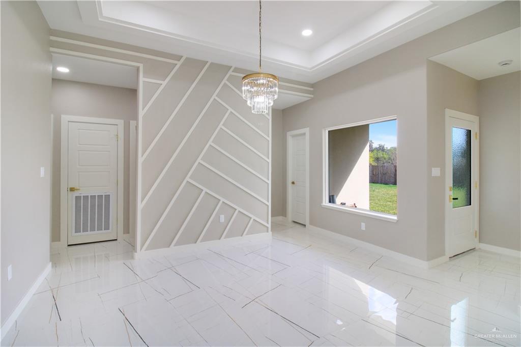 909 Azalea Street Mission, TX 78573 - Photo 7 of 29 Unfurnished dining area featuring a chandelier and a raised ceiling,door by the window has exit to the yard