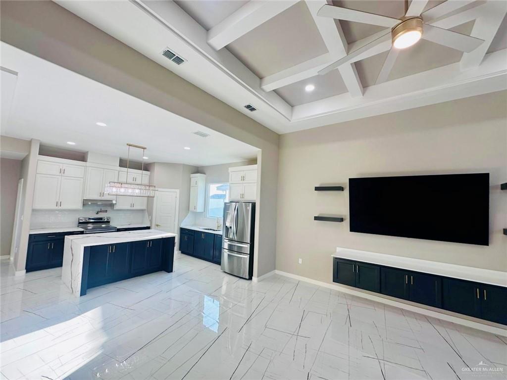909 Azalea Street Mission, TX 78573 - Photo 10 of 29 Kitchen with dual tone cabinets, stainless steel appliances, coffered ceiling, light stone countertops, and light beautiful flooring