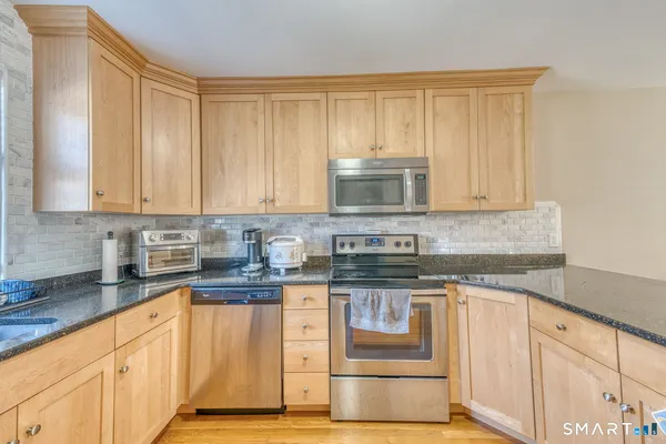 a kitchen with granite countertop white cabinets and stainless steel appliances