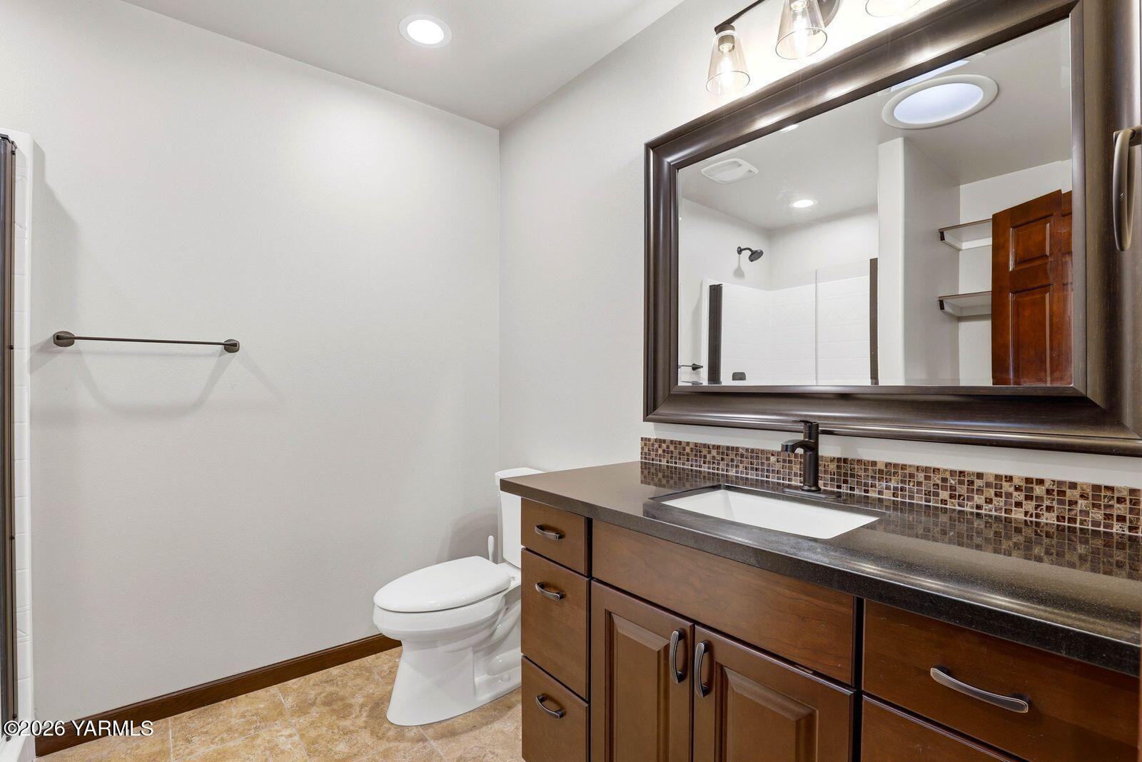 13507 West Church Road Yakima, WA 98903 - Photo 29 of 46 a bathroom with a granite countertop sink a toilet and a mirror