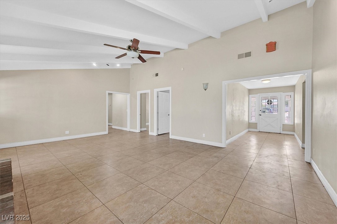 6384 West Desert Inn Road Las Vegas, NV 89146 - Photo 2 of 26 Unfurnished room with light tile patterned floors, beamed ceiling, ceiling fan, and high vaulted ceiling