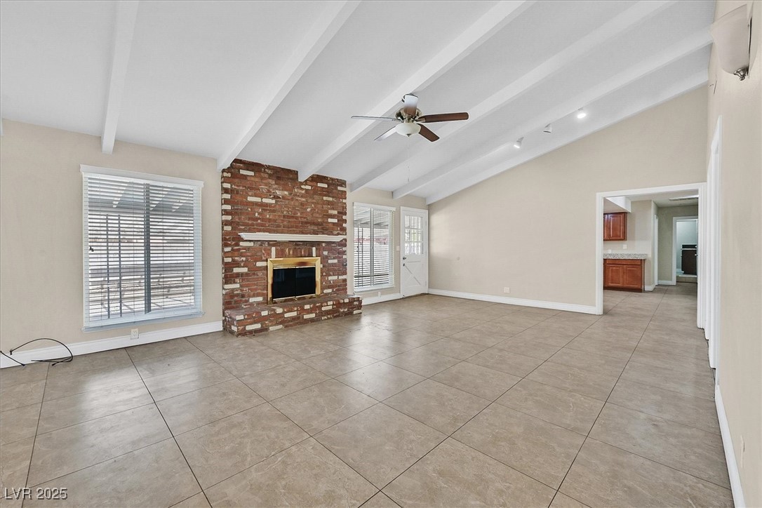 6384 West Desert Inn Road Las Vegas, NV 89146 - Photo 3 of 26 Unfurnished living room with a brick fireplace, light tile patterned floors, and a ceiling fan