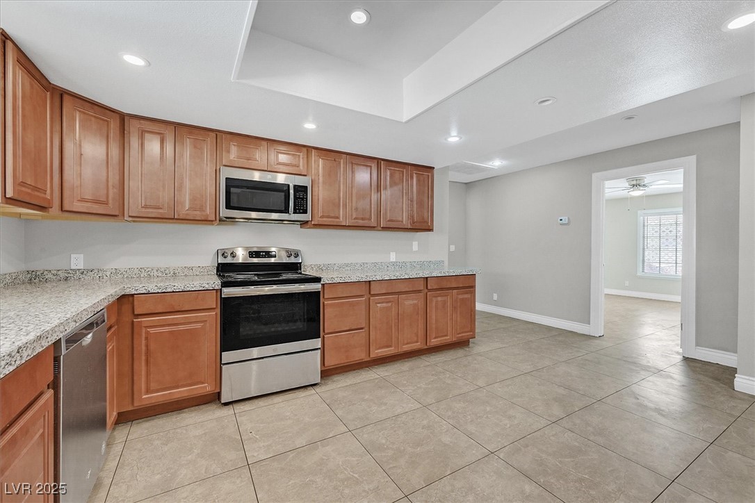 6384 West Desert Inn Road Las Vegas, NV 89146 - Photo 6 of 26 Kitchen featuring appliances with stainless steel finishes, brown cabinetry, recessed lighting, light tile patterned flooring, and a ceiling fan