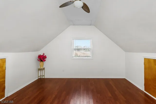an empty room with wooden floor ceiling fan and windows