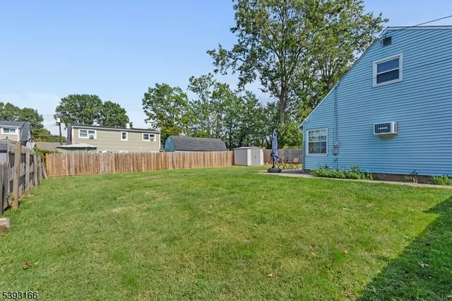 a view of a backyard with large trees and wooden fence