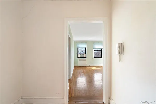 a view of a hallway with wooden floor and a bathroom