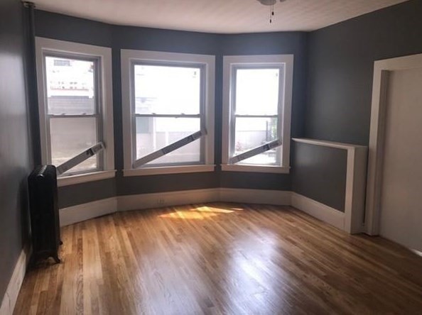 78 Downing Street Worcester, MA 01610 - Photo 4 of 11 an empty room with wooden floor and windows