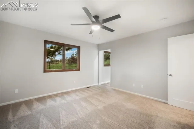 an empty room with window and ceiling fan