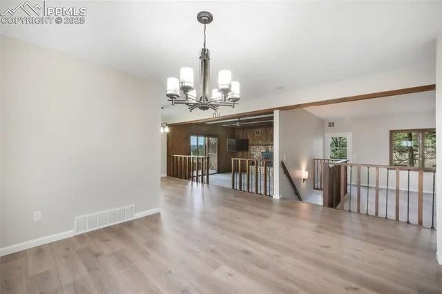 a view of a room with wooden floor chandelier and windows