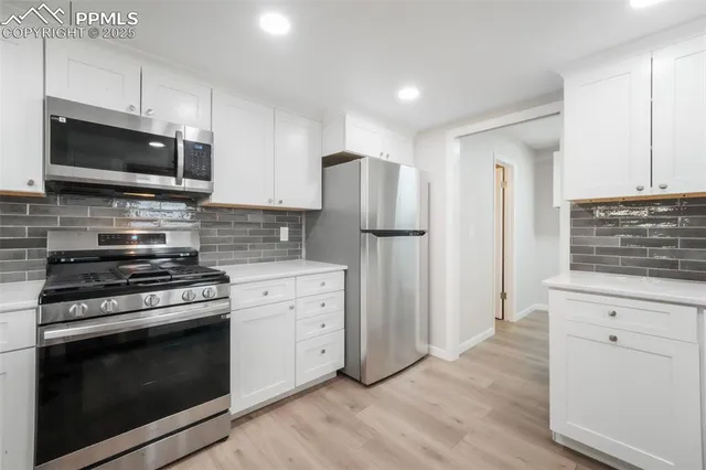 a kitchen with stainless steel appliances white cabinets and a stove top oven