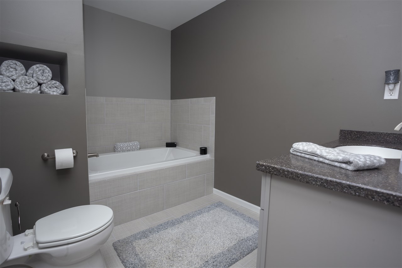 7634 Jockey Drive Loves Park, IL 61111 - Photo 22 of 25 a bathroom with a granite countertop toilet and a bathtub