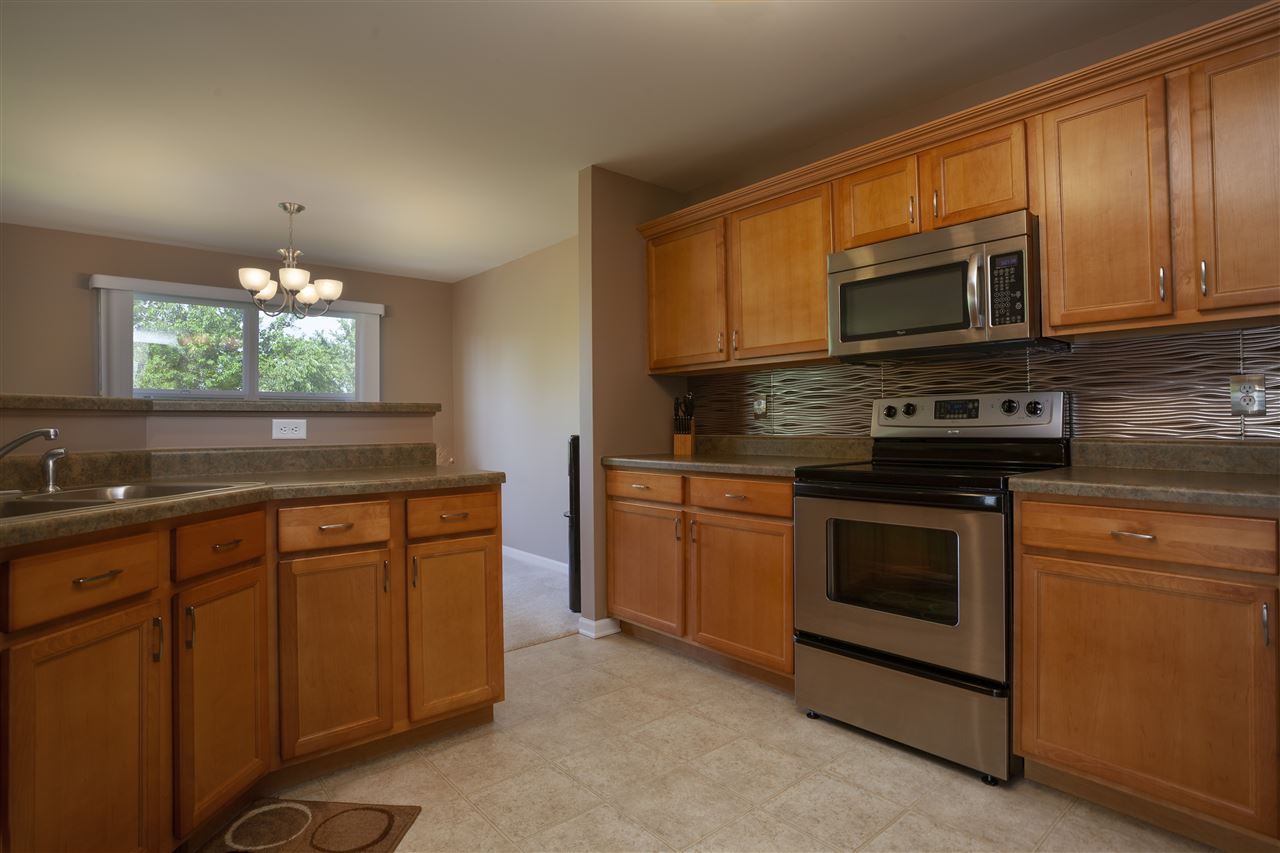 7634 Jockey Drive Loves Park, IL 61111 - Photo 8 of 25 a kitchen with stainless steel appliances granite countertop a stove microwave and sink