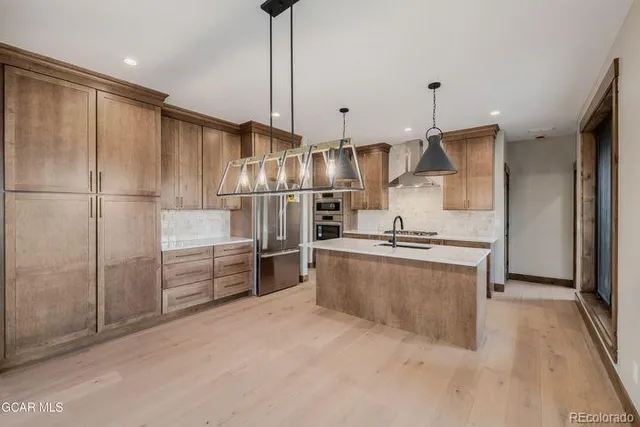 a kitchen with stainless steel appliances granite countertop a sink a stove and a refrigerator