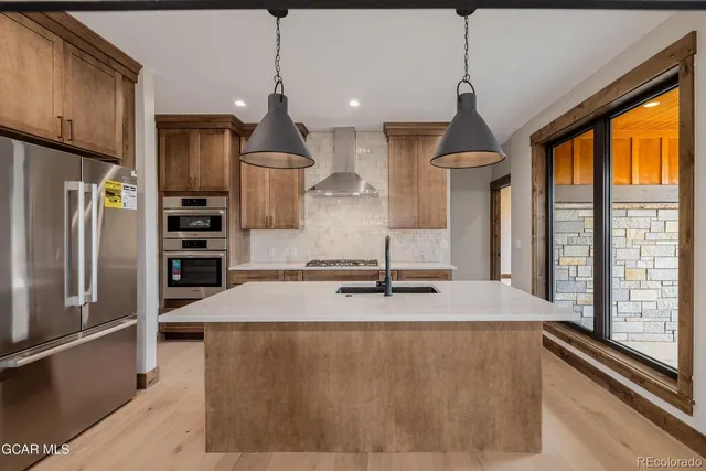 a kitchen with stainless steel appliances granite countertop a sink a refrigerator and a stove