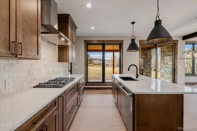 a kitchen with stainless steel appliances a sink a stove and a wooden floors