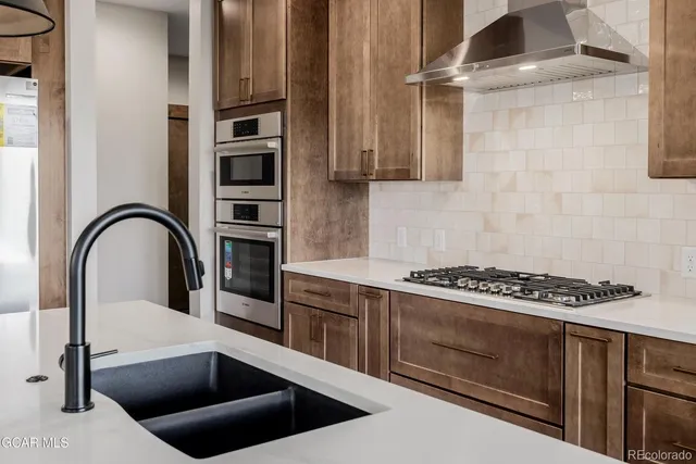 a large kitchen with stainless steel appliances kitchen island granite countertop a refrigerator and a sink