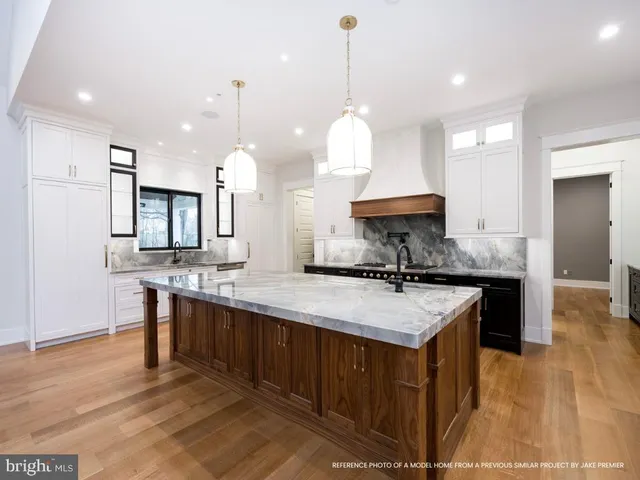 a kitchen with stainless steel appliances granite countertop a stove a sink a center island and a wooden floor