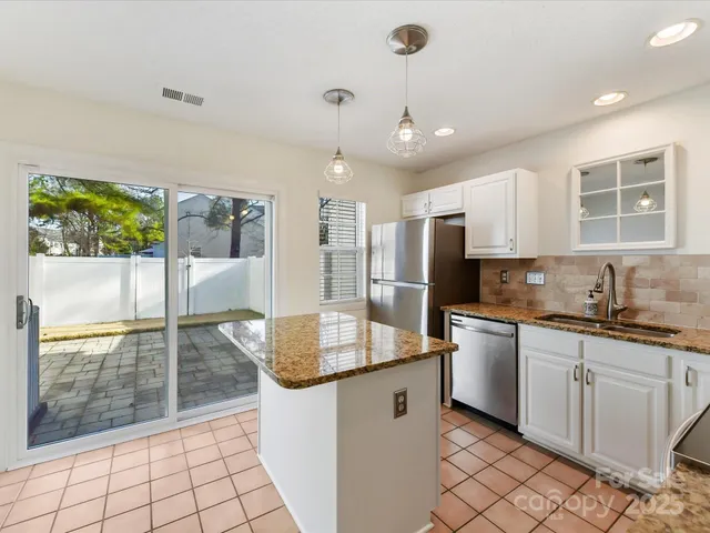 a kitchen with granite countertop a sink a counter top space appliances and cabinets