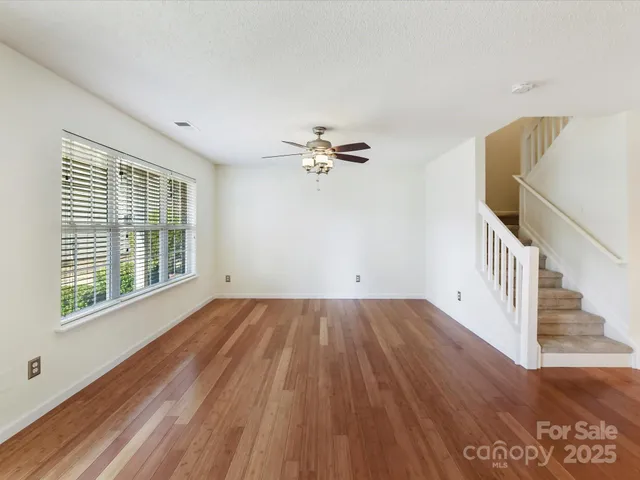 a view of a livingroom with wooden floor and a ceiling fan