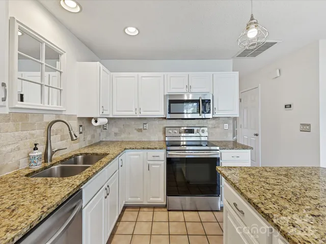 a kitchen with kitchen island granite countertop a sink stove top oven and cabinets
