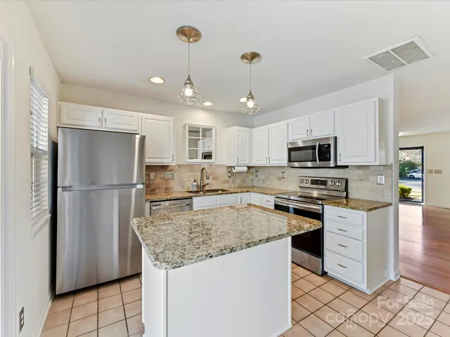 a kitchen with stainless steel appliances granite countertop a refrigerator a sink a stove a microwave and island