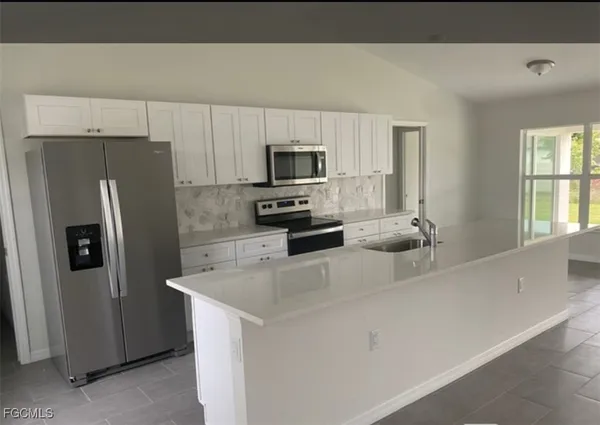 a kitchen with stainless steel appliances a refrigerator sink and microwave