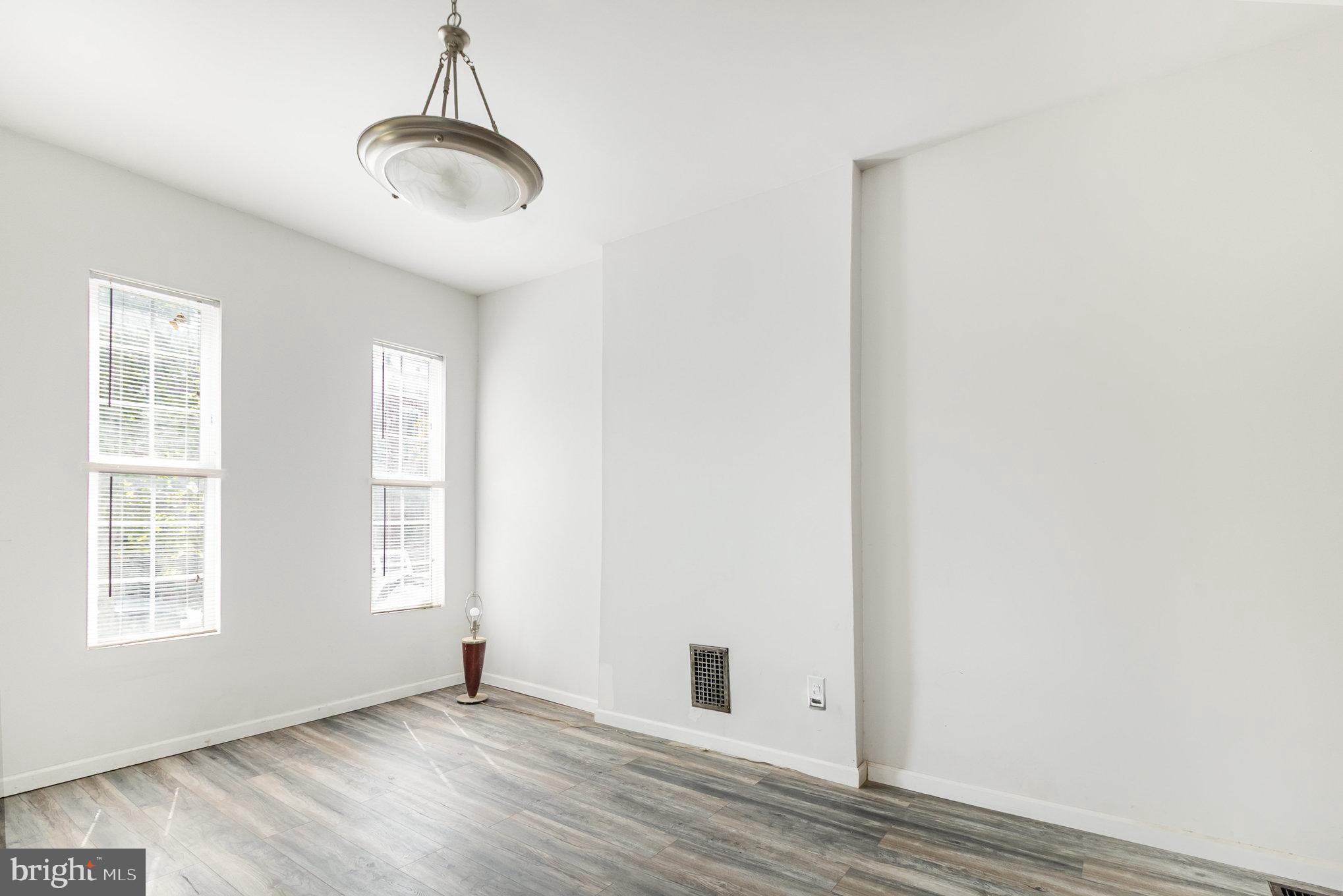2544 West Fairmount Avenue Baltimore, MD 21223 - Photo 7 of 20 an empty room with wooden floor exposed radiator and windows