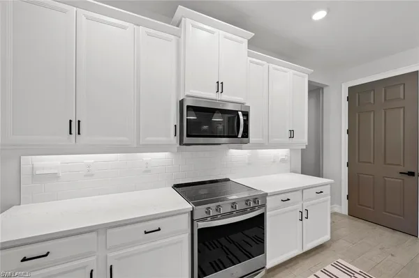 a kitchen with white cabinets and stainless steel appliances