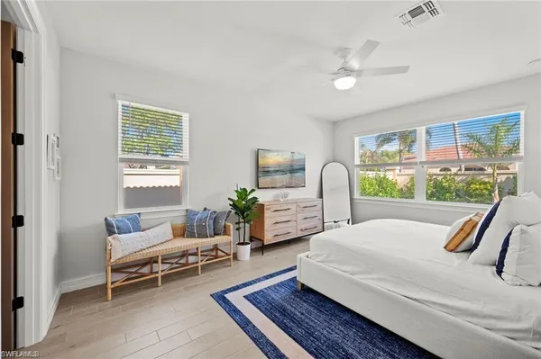 a bedroom with a bed wooden floor and a large window
