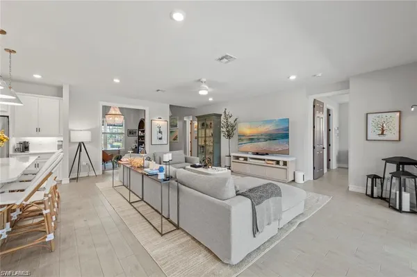 a living room with furniture kitchen view and a flat screen tv
